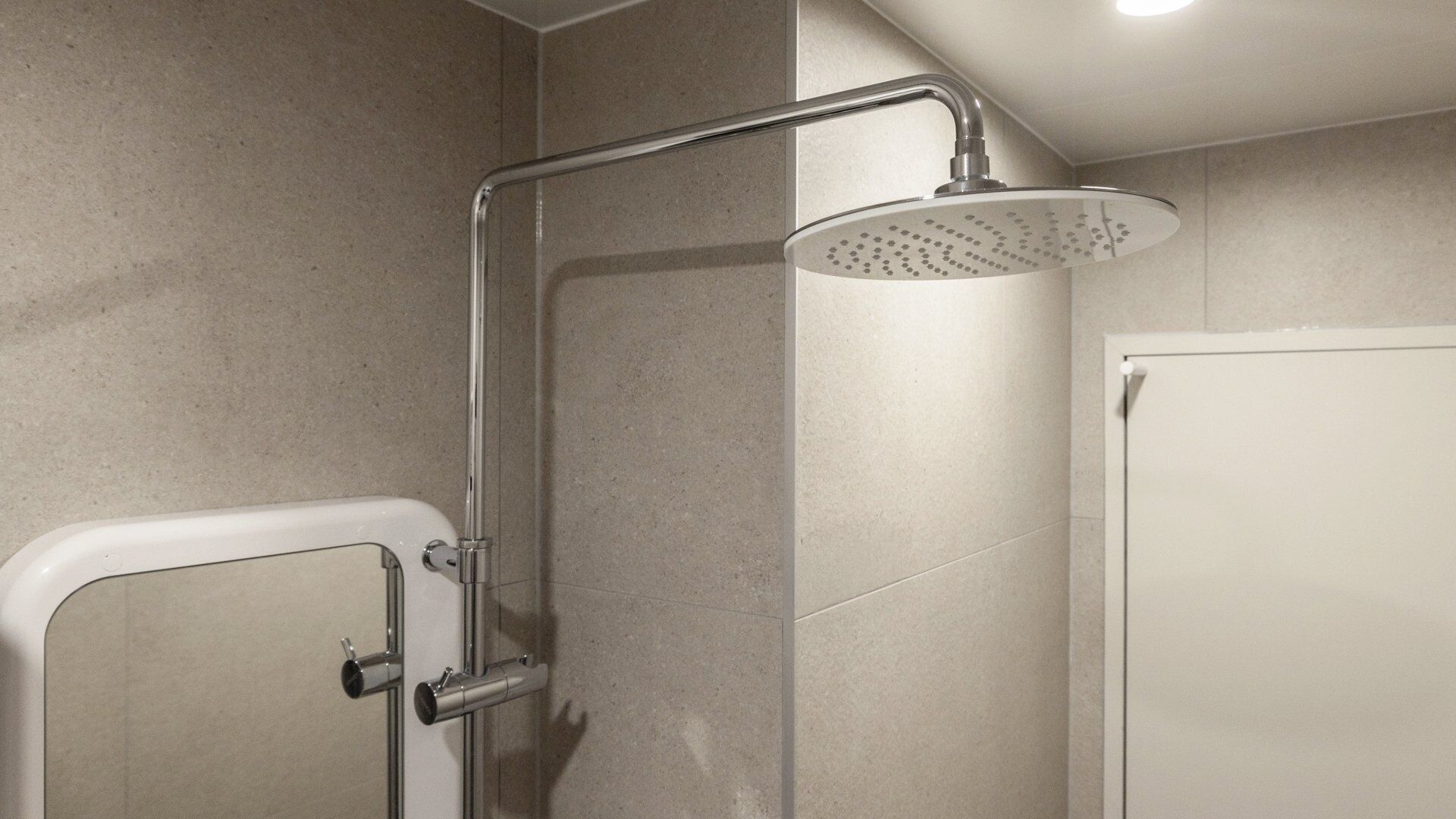 Cabina de ducha con ducha de mano y grifería empotrada.