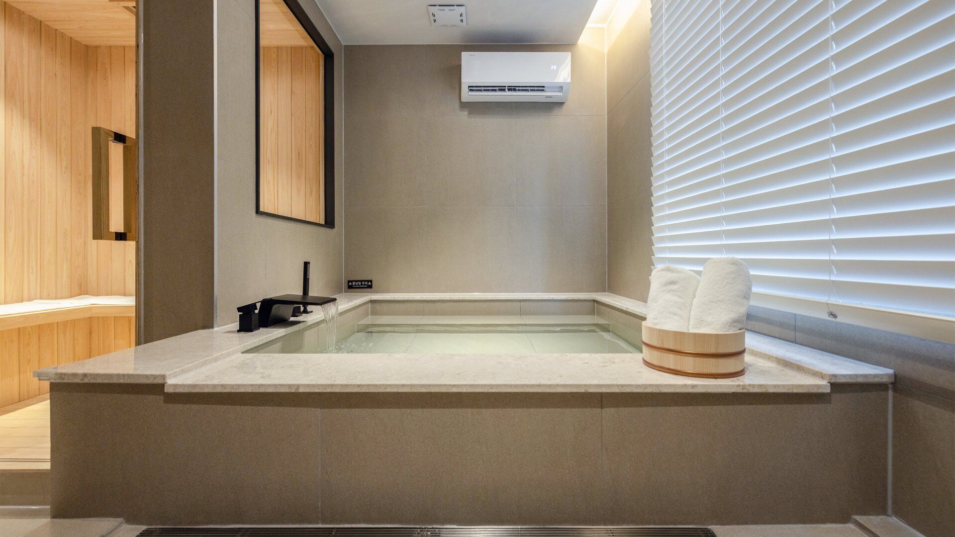 Ein modernes Badezimmer mit freistehender Badewanne, Handtuchhalter und Wand-Klimaanlage.