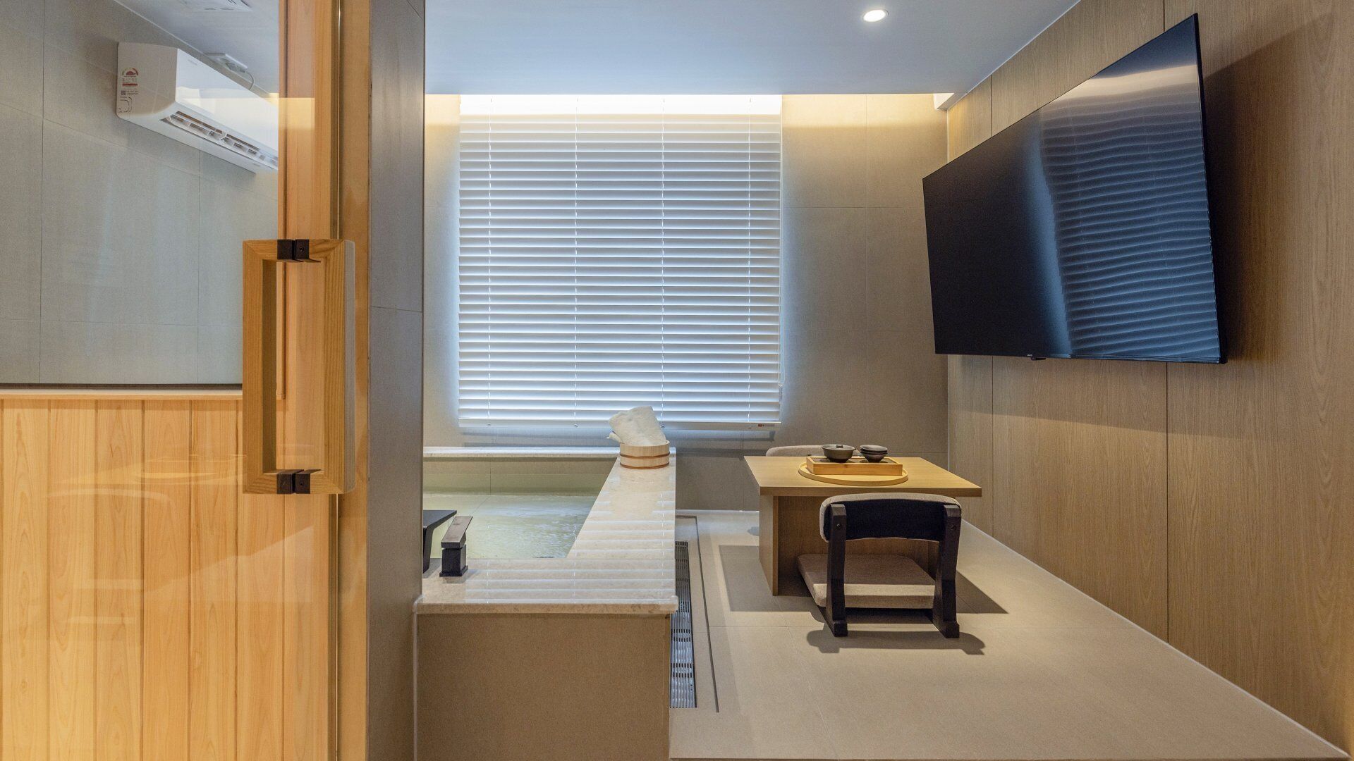 Un baño moderno con tocador de madera, bañera y un ventanal con persianas.