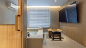 Un baño moderno con tocador de madera, bañera y un ventanal con persianas.