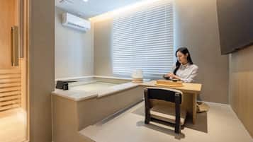 A modern bathroom with a bathtub, a towel rack, and a window with blinds.