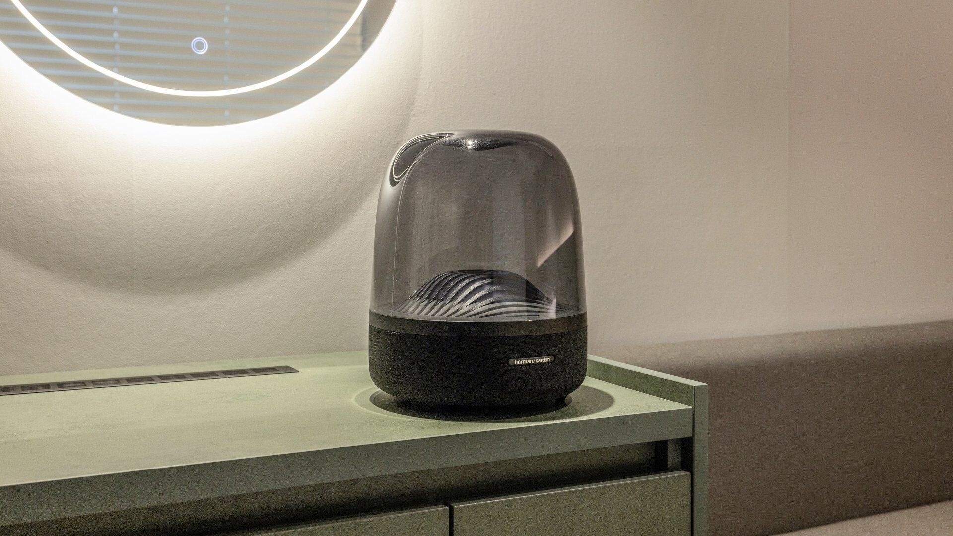 Una habitación moderna y minimalista con un objeto liso y negro con forma de cúpula sobre una superficie verde clara, posiblemente un mueble o un adorno.