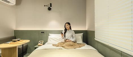 Habitación de hotel con cama, mesita de noche y lámpara de pared.