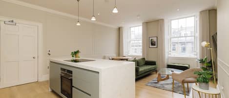 A modern kitchen with a central island, built-in appliances, and pendant lighting.