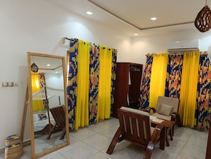 Una habitación con una cama, una silla de madera, una mesa de comedor y un espejo.