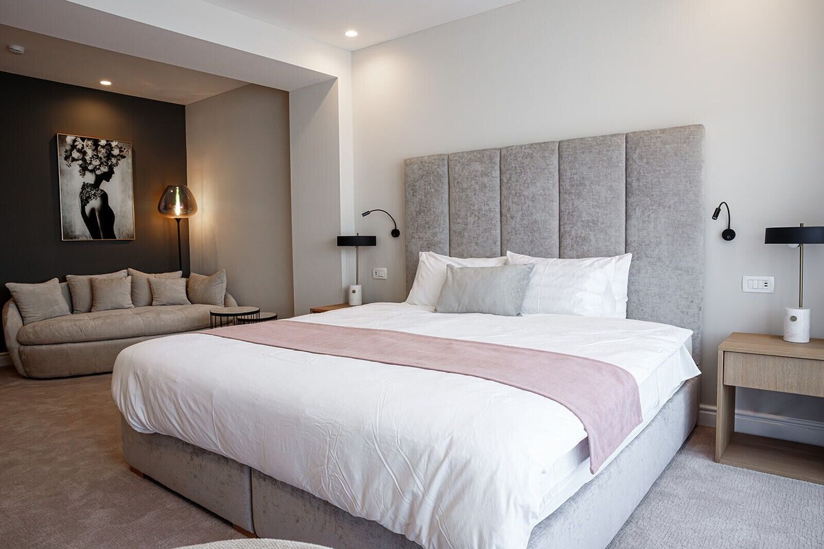 Ein modernes Schlafzimmer mit einem großen Bett, einer Couch und einem Nachttisch.