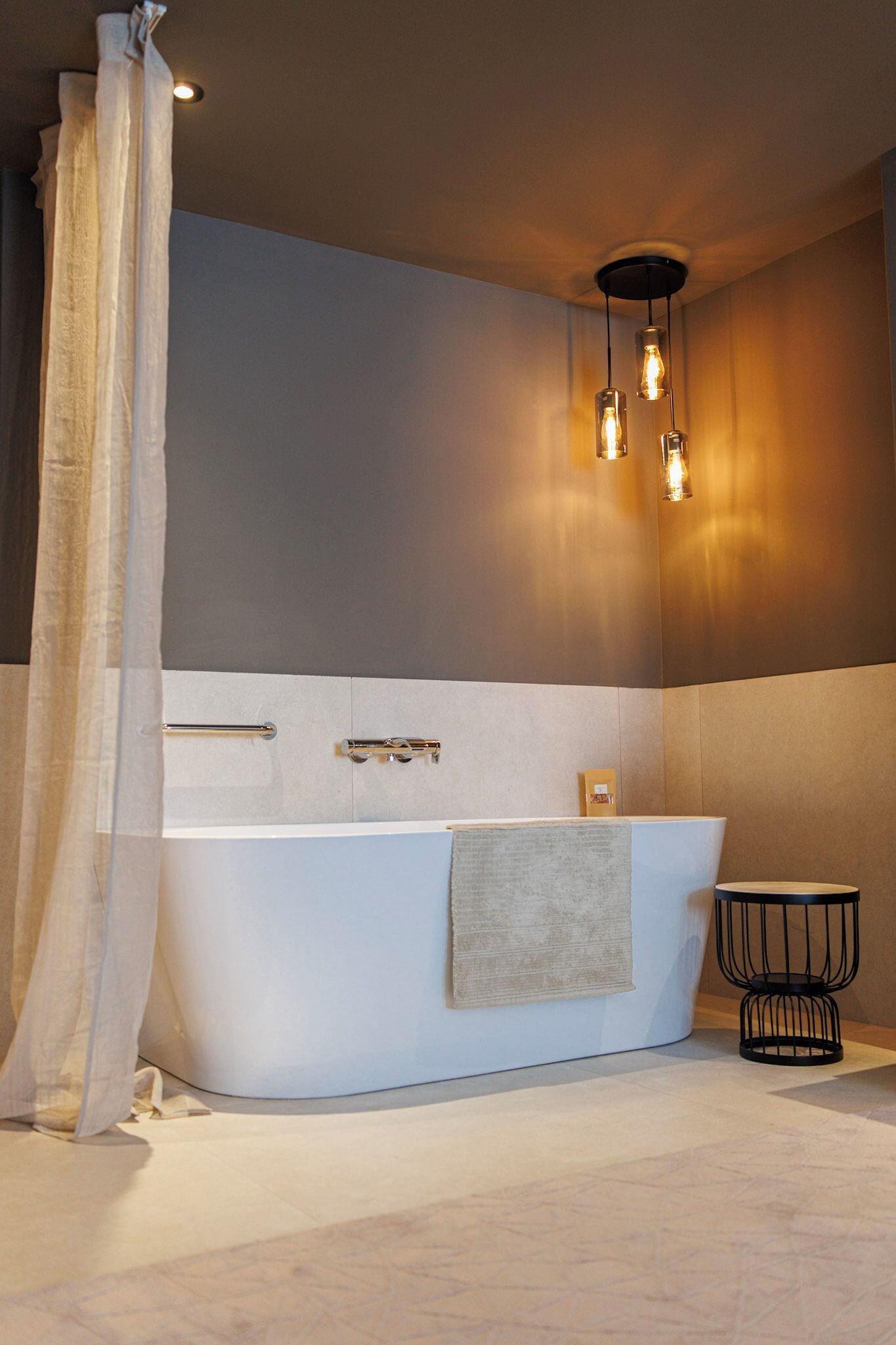 A modern bathroom with a freestanding bathtub, a towel rack, and a small stool.