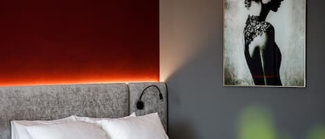 Una habitación de hotel con una cama, una mesita de noche y una obra de arte colgada en la pared.