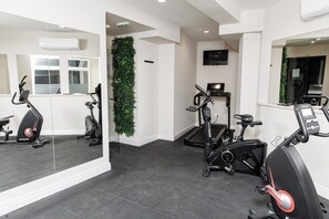A gym with exercise bikes, a treadmill, and a mirrored wall.