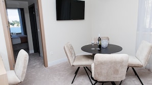 A room with a round table, four chairs, a television on the wall, and a view of the outdoors. - Hotel M (ZATON)