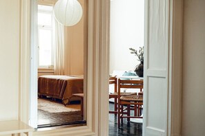 Ein Zimmer mit einem Bett, einem Esstisch mit Stühlen und einer Pendelleuchte.