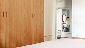 Un dormitorio con una cama grande, un armario de madera y una puerta que da al baño.