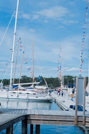 A marina with multiple sailboats docked, a wooden pier, and a clear sky.