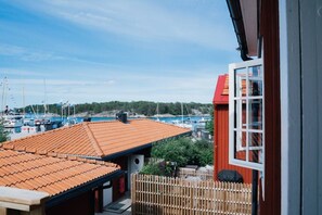 A coastal property with a red-roofed building, a wooden fence, and a view of boats in the distance.