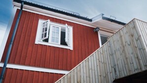 Punainen rakennus, jossa on valkoinen ikkuna ja puinen portaikko.