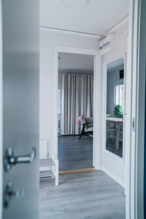 Ein Flur, der zu einem Zimmer mit Schreibtisch, Stuhl und Vorhängen führt.