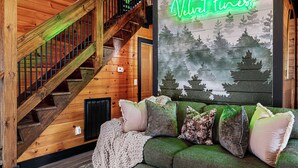 A wooden staircase with a neon sign reading 'Velvet Pines' above a green sofa with multiple cushions. - Velvet Pines | Lake Front | Amenities Galore | 5* (Pigeon Forge)