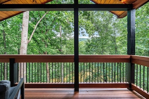 A wooden deck with a metal railing, surrounded by trees. - Velvet Pines | Lake Front | Amenities Galore | 5* (Pigeon Forge)