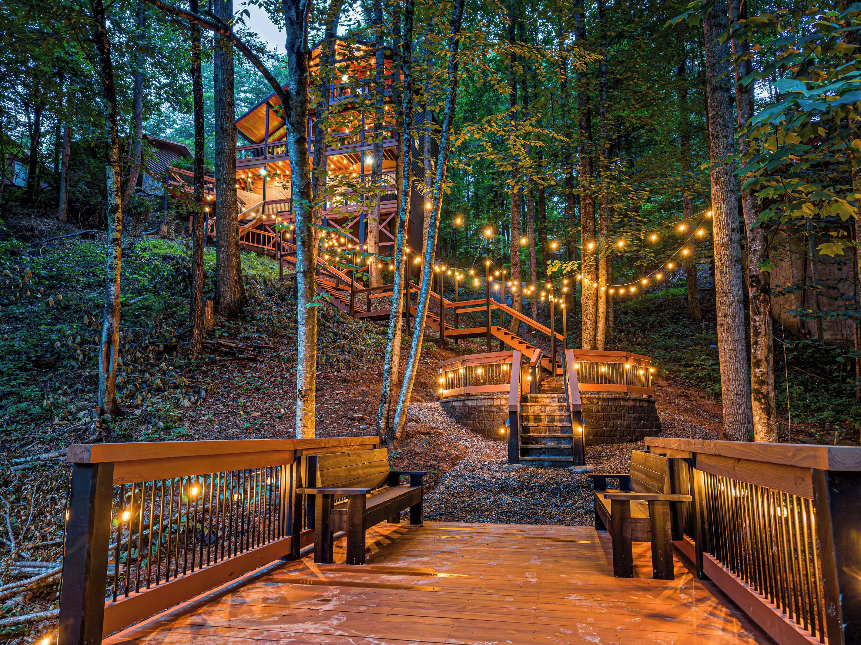 A wooden deck with a railing, leading to a staircase surrounded by trees.