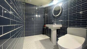 A bathroom with dark blue tiled walls, a white sink, and a toilet.