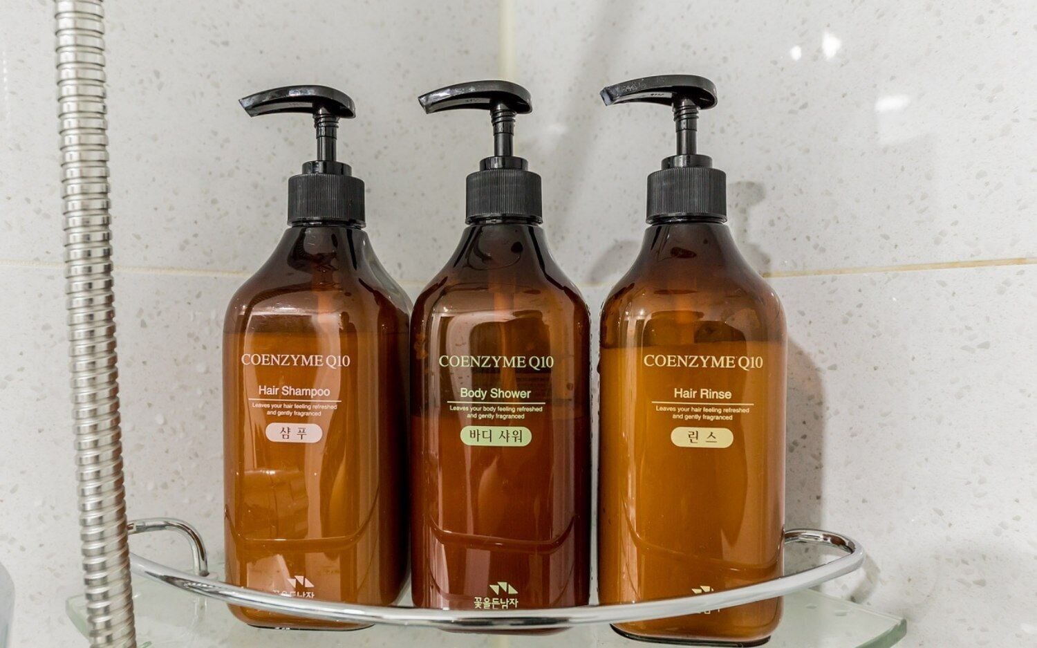 Three bottles of Coenzyme Q10 hair care products on a bathroom shelf.