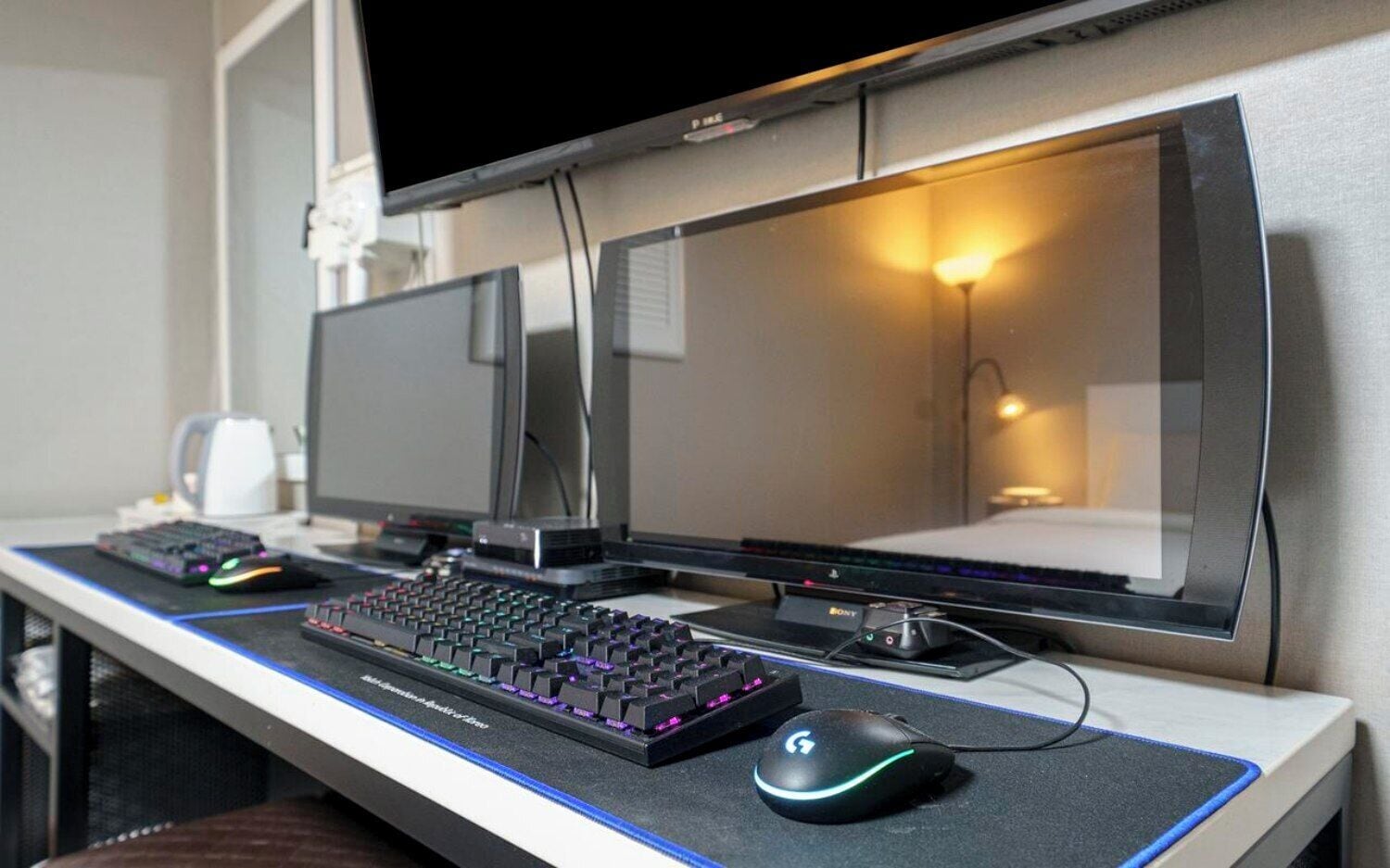 Una estación de juego con dos monitores, un teclado mecánico y un ratón sobre un escritorio.