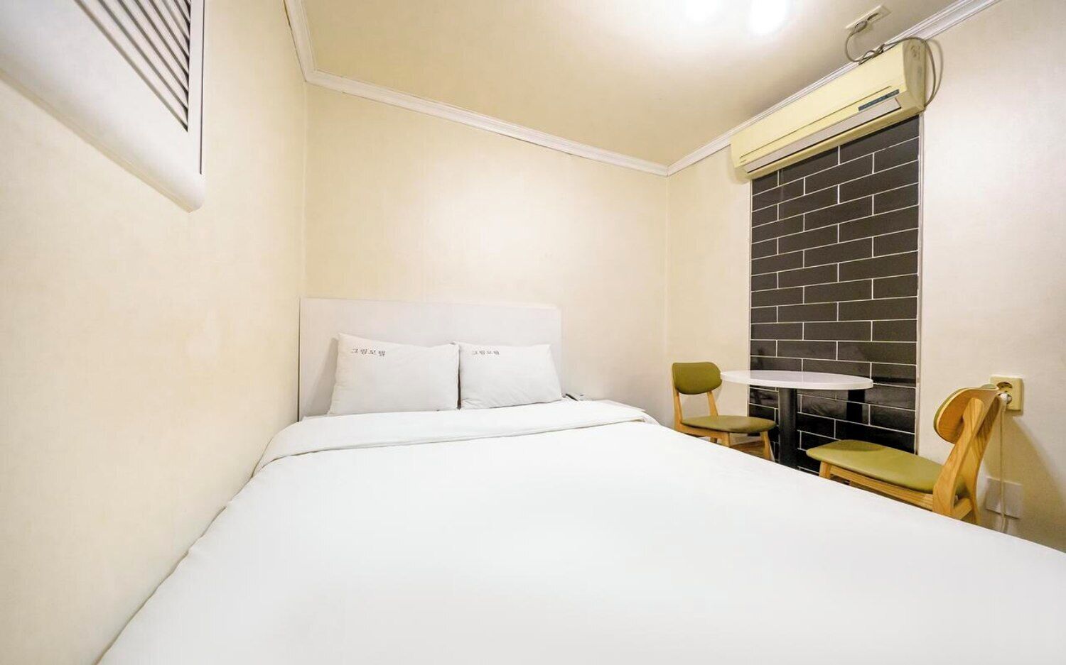A hotel room with a bed, a small table, and a chair.