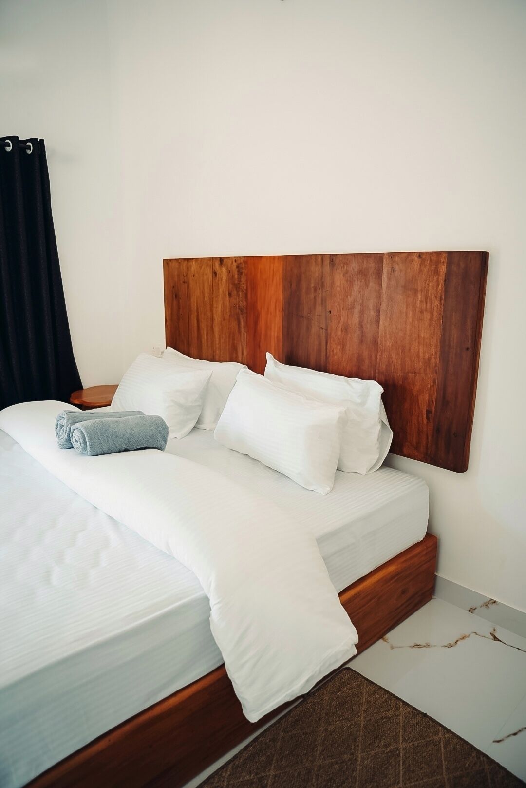 A neatly made bed with white linens and a wooden headboard.