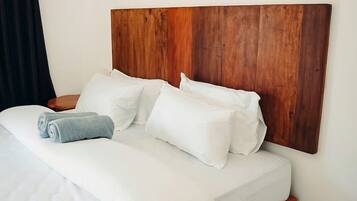 A neatly made bed with white linens and a wooden headboard.