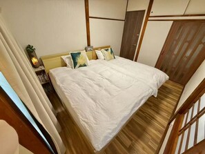 A bedroom with a bed, wooden floor, and a wardrobe. - Tokyo Star House-Shinkoiwa (Katsushika City)