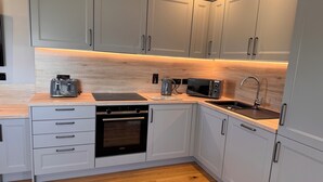 A modern kitchen with grey cabinets, a black oven, a microwave, and a sink.