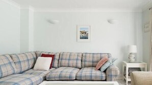 A living room with a sectional sofa, a coffee table, a side table with a lamp, and a framed picture on the wall. - Viking Bay House with Parking and Mins to Viking Bay Beach & Broadstairs Town (Broadstairs)