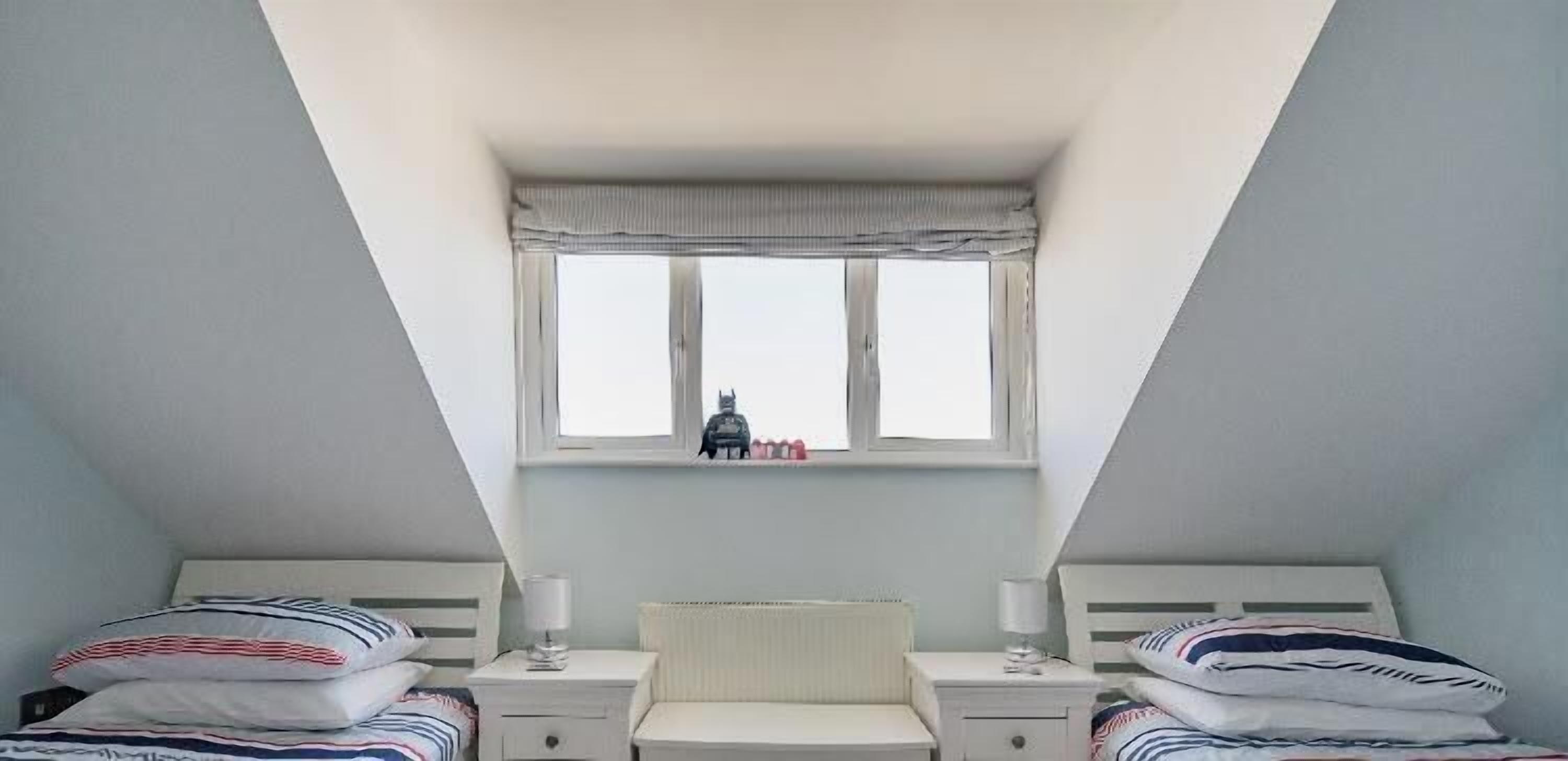 Une chambre avec deux lits, une fenêtre et une vue sur une statue.