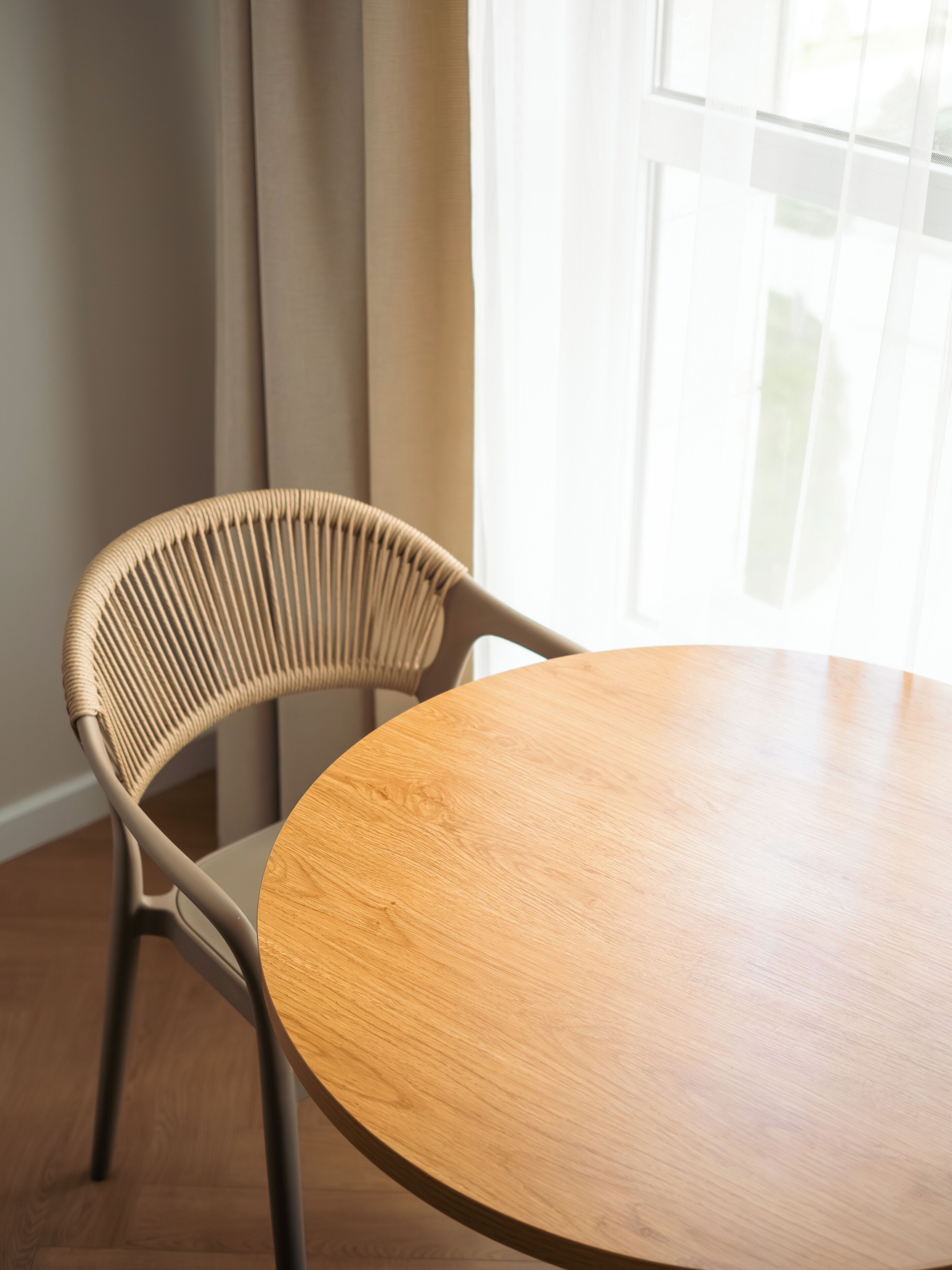 A round wooden table with a woven chair.
