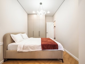 A bedroom with a bed, wardrobe, and a door leading to another room. - Comfort City Resedential Complex (Almaty)