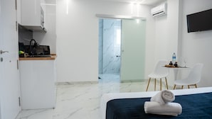 A modern hotel room with a bed, a desk, a chair, and a bathroom visible through a glass door. - AP Alsa 01 with Shared Terrace, WiFi, and Air Conditioning (Conil de la Frontera)