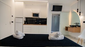 A hotel room with a bed, two towels, a microwave, a refrigerator, a sink, and a TV. - AP Alsa 2.3 with Shared Terrace, WiFi, and Air Conditioning (Conil de la Frontera)