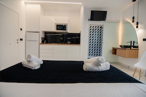 A hotel room with a bed, two towels, a microwave, a refrigerator, a sink, and a TV. - AP Alsa 2.3 with Shared Terrace, WiFi, and Air Conditioning (Conil de la Frontera)