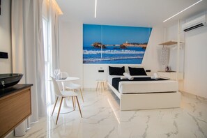 A modern bedroom with a bed, a desk, and a chair, a painting of a coastal scene, and an air conditioning unit. - AP Alsa 2.3 with Shared Terrace, WiFi, and Air Conditioning (Conil de la Frontera)
