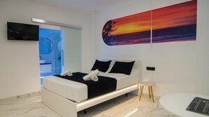A modern bedroom with a bed, a bedside table, a wall-mounted TV, and a large abstract painting. - AP Alsa 2.1 with Shared Terrace, WiFi and Air Conditioning (Conil de la Frontera)