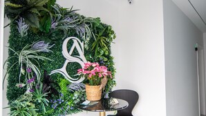 A reception area with a wall-mounted plant wall, a decorative letter, a small table with a basket of flowers, and a black chair. - AP Alsa 2.1 with Shared Terrace, WiFi and Air Conditioning (Conil de la Frontera)