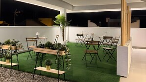 An outdoor event space with a white tent, green artificial turf, wooden tables with chairs, and potted plants. - AP Alsa 2.1 with Shared Terrace, WiFi and Air Conditioning (Conil de la Frontera)