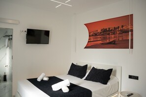 Ein modernes Hotelzimmer mit einem Bett, einem Flachbildfernseher, einem großen gerahmten Bild und einem Badezimmer mit Marmorwand.