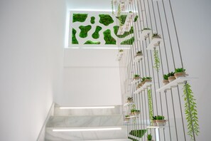 Eine Treppe mit weißer Geländer, Blumentöpfen und einem grünen Wandkunstwerk.