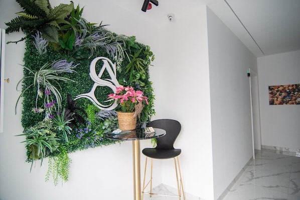 A modern interior with a green wall adorned with various plants and a decorative metal sign.