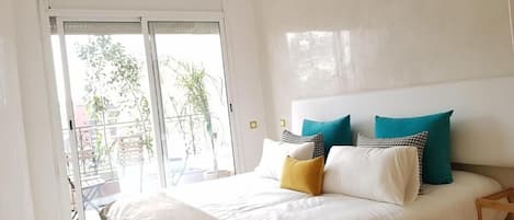 A bedroom with a bed, pillows, a nightstand, and a sliding glass door leading to an outdoor area.