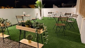 An outdoor patio area with artificial grass, wooden tables and chairs, and potted plants. - AP Alsa 1.3 with Shared Terrace, WiFi and Air Conditioning (Conil de la Frontera)