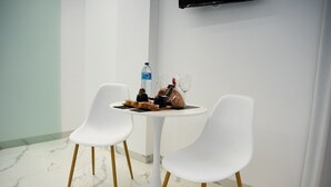 A small round table with two white chairs, a bottle of water, and a glass. - AP Alsa 1.3 with Shared Terrace, WiFi and Air Conditioning (Conil de la Frontera)