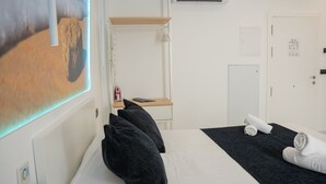 A hotel room with a bed, a desk, a chair, a wall-mounted TV, and a door. - AP Alsa 1.3 with Shared Terrace, WiFi and Air Conditioning (Conil de la Frontera)