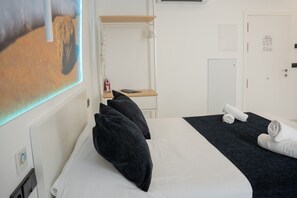 Ein Hotelzimmer mit einem Bett, einem Schreibtisch, einem Stuhl, einem an der Wand befestigten Fernseher und einer Tür.